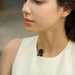 Close-up of a person wearing a white sleeveless top with a black microphone attached to their collarbone.