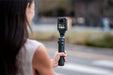 Person holding a camera on a stabilizer with a blurred outdoor background