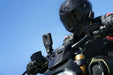 Motorcyclist wearing a helmet with a mounted camera on a clear blue sky background