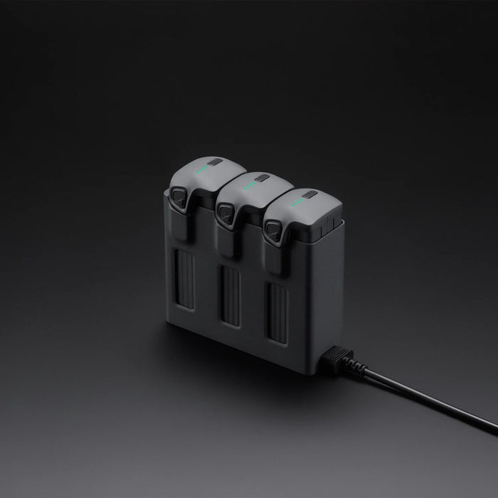 Black battery charger with three battery slots on a dark background