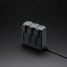 Black battery charger with three battery slots on a dark background